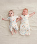 Two babies wearing an ergoPouch Short Sleeve Layer and a Cocoon Swaddle Bag
