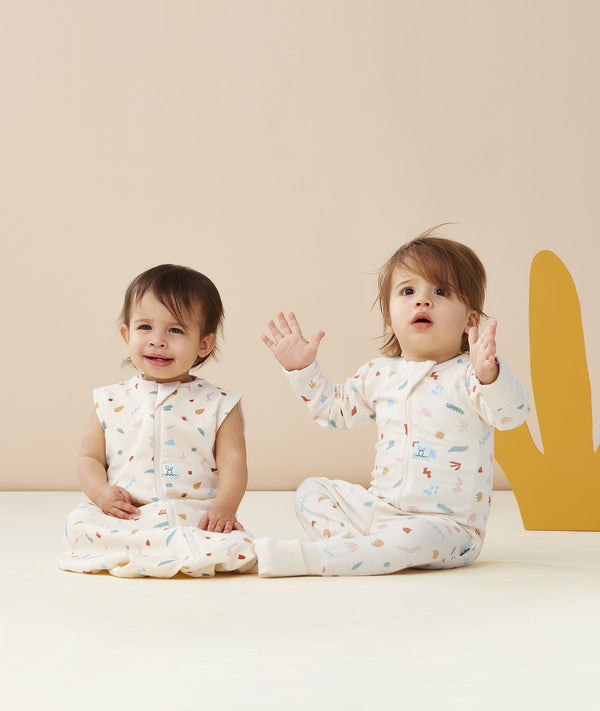 Two infants wearing ergoPouch sleepwear. One wearing a Sleeping Bag while the other wearing a Long Sleeve Layer.