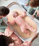 Easy Sleep Portable Bassinet Ecru newborn lying surrounded by family