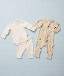 Two sets of ergoPouch baby sleepwear laid out on a light blue background. On the left is a long sleeve two-piece pyjamas in Oatmeal Marle. On the right is a long sleeve leyer, decorated with a colorful animal print.