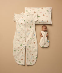 A flat lay display features a Sleep Suit Bag with a colorful safari animal print, a Toddler Pillow and Case with the same print, and a baby doll dressed in a doll-sized sleeping bag featuring the same safari animal pattern.
