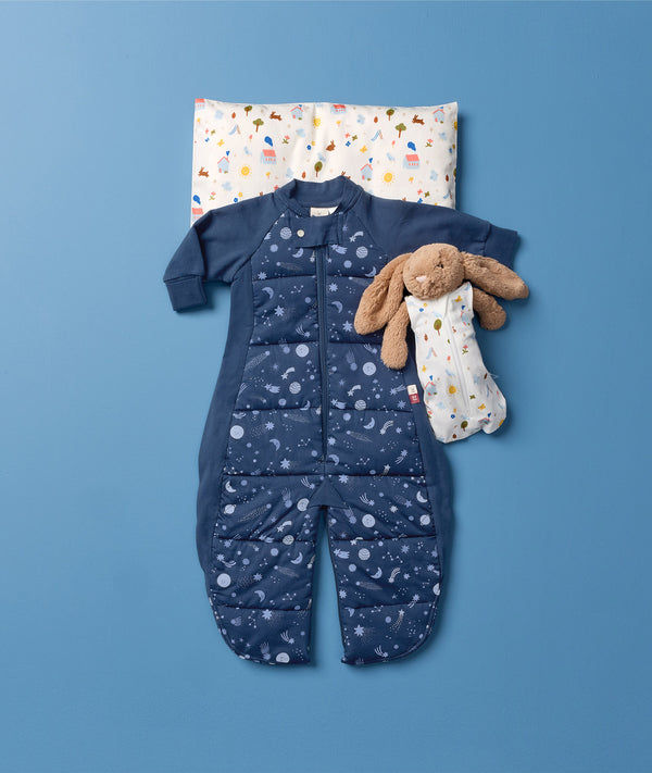 Flatlay of the ergoPouch  Sleep Suit Bag 3.5 TOG, Toddler Pillow in Daydream, with a teddy bear dressed in a Doll Sleeping Bag