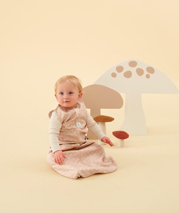 Infant sitting upright wearing an ergoPouch Sleeping Bag with a long sleeve layer underneath