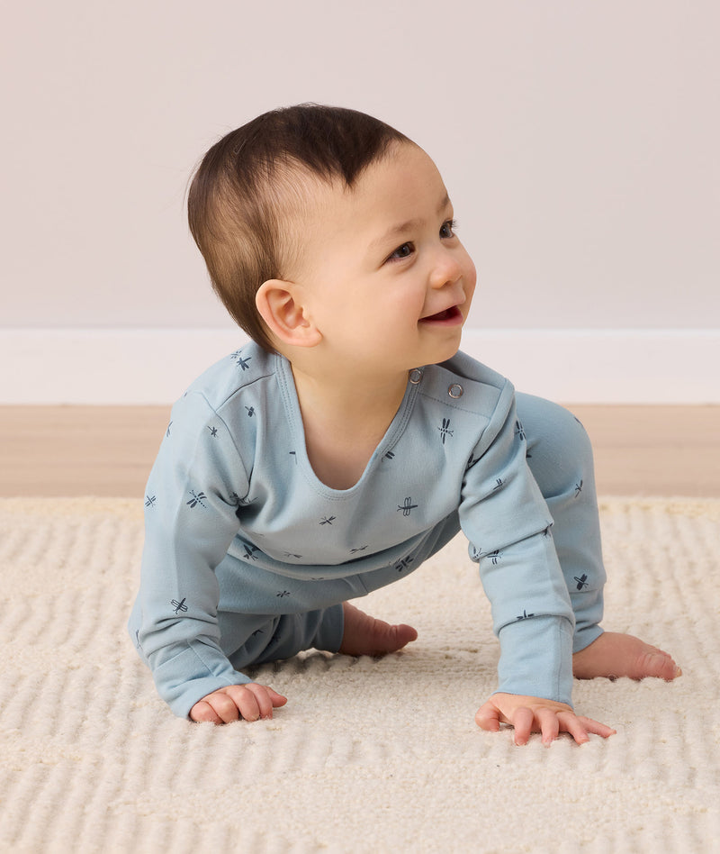 A crawling baby is wearing light blue, long-sleeved, two-piece pyjamas.