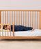 Toddler lying on their side in a crib wearing a navy blue long-sleeve pyjama set with matching pants, featuring a relaxed fit.