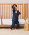 Toddler standing and playing beside a toddler bed, wearing a navy blue long-sleeve pyjama set with matching pants, featuring a relaxed fit and soft fabric.