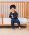 Toddler sitting on a bed wearing a navy blue Long Sleeve Pyjamas with matching pants, featuring a soft breathable fabric.
