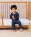 Toddler sitting on a bed wearing a navy blue Long Sleeve Pyjamas with matching pants, featuring a soft breathable fabric.