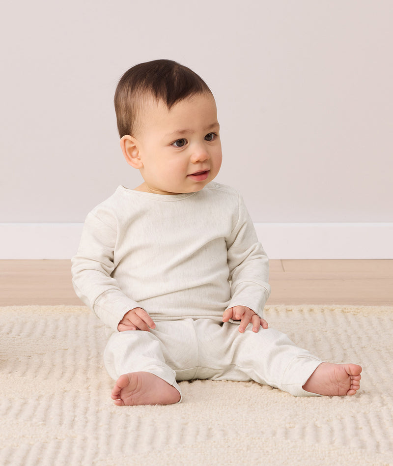 Infant sitting on a rug wearing an ergoPouch Long Sleeve Baby Pyjamas