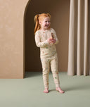 A preschooler is smiling while wearing snug-fitting, safari-themed long sleeve pyjamas from ergoPouch.
