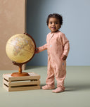 Toddler standing next to a globe, dressed in ergoPouch Long Sleeve Layer Elephant Parade