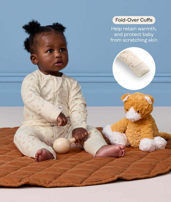 Baby sitting on a mat in a cream Long Sleeve Layer next to a plush toy, with a feature highlight on 