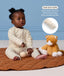 Baby sitting on a mat in a cream Long Sleeve Layer next to a plush toy, with a feature highlight on 
