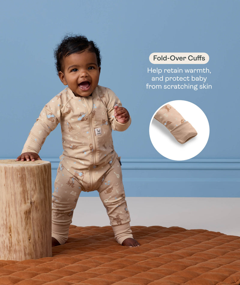 Baby wearing a patterned tan Long Sleeve Layer leaning against a wooden stool featuring text highlighting fold-over cuffs.