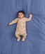 Sleeping baby lying on a blue blanket wearing a beige patterned Long-Sleeve Layer with fold-over foot cuffs.