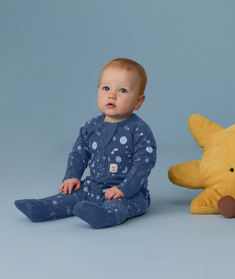 Baby wearing a blue Long Sleeve Layer with star and moon print, sitting upright against a light blue background.