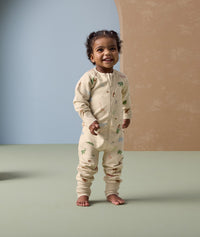 Smiling toddler in ergoPouch Long Sleeve Layer Savannah, featuring a front zipper and safari animal print.