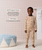 Preschooler standing and smiling in a beige patterned Long Seeve Pyjama set with product feature callout highlighting GOTS organic cotton and TOG rating