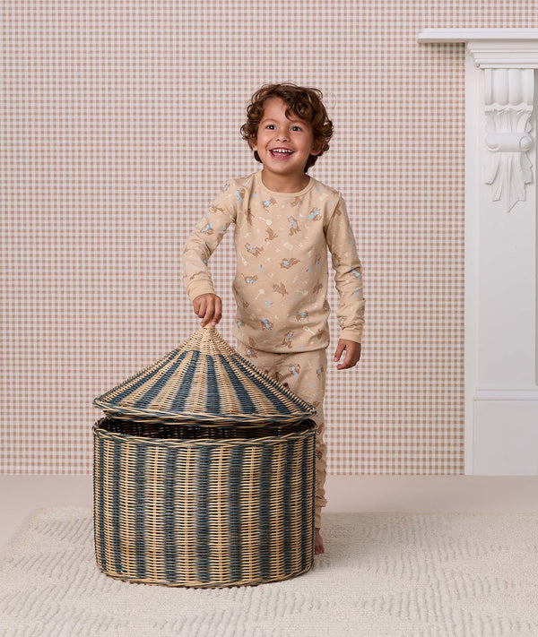 Preschooler wearing a beige printed Long Sleeve Pyjama set opening a striped woven storage basket.