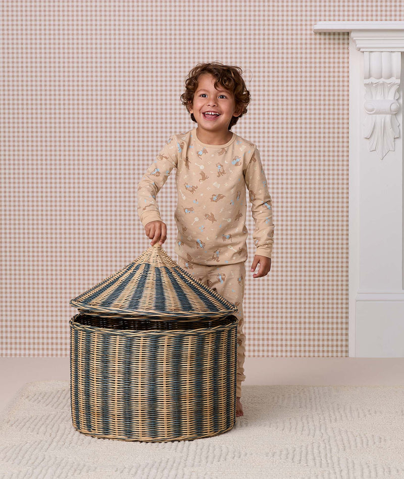 Preschooler wearing a beige printed Long Sleeve Pyjama set opening a striped woven storage basket.