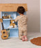 Child wearing a beige patterned Long Sleeve Pyjamas kneeling in front of a wooden dollhouse.