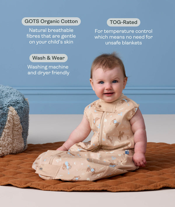 Baby sitting upright wearing a Premium Sleeping Bag with callouts highlighting 