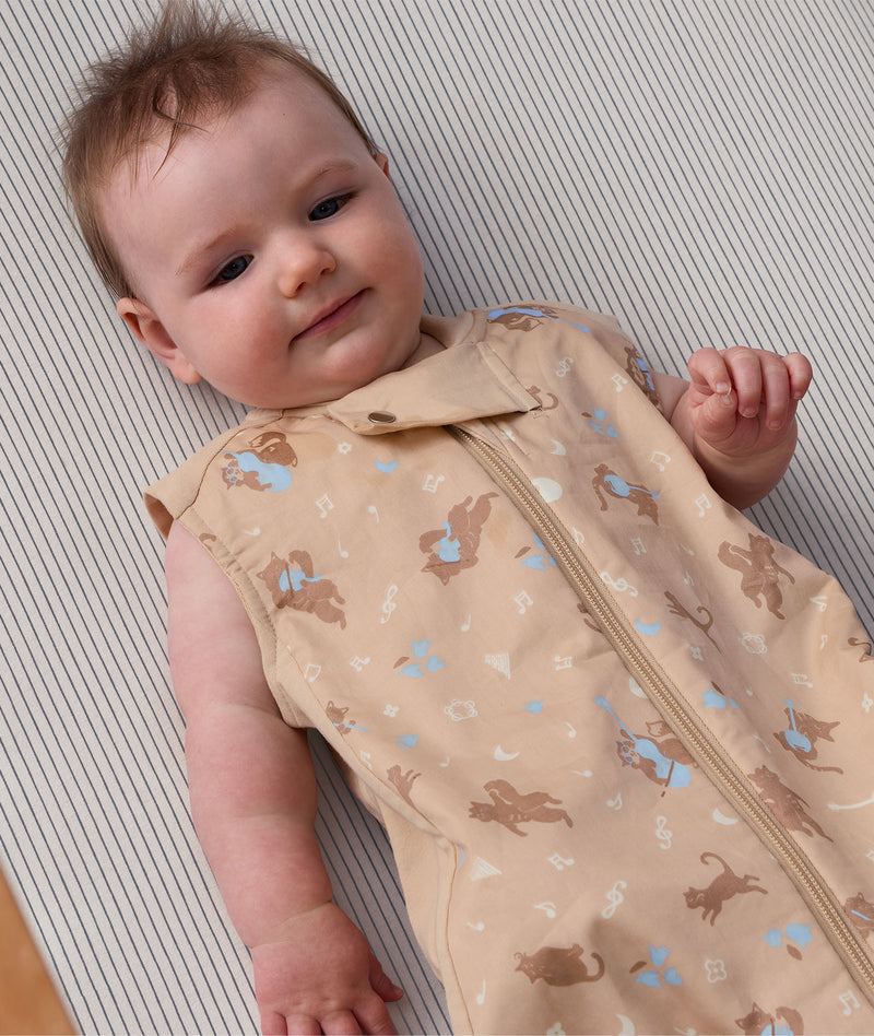 Close up of a baby wearing a Premium Sleeping Bag 1.0 TOG featuring a front zipper and animal print.