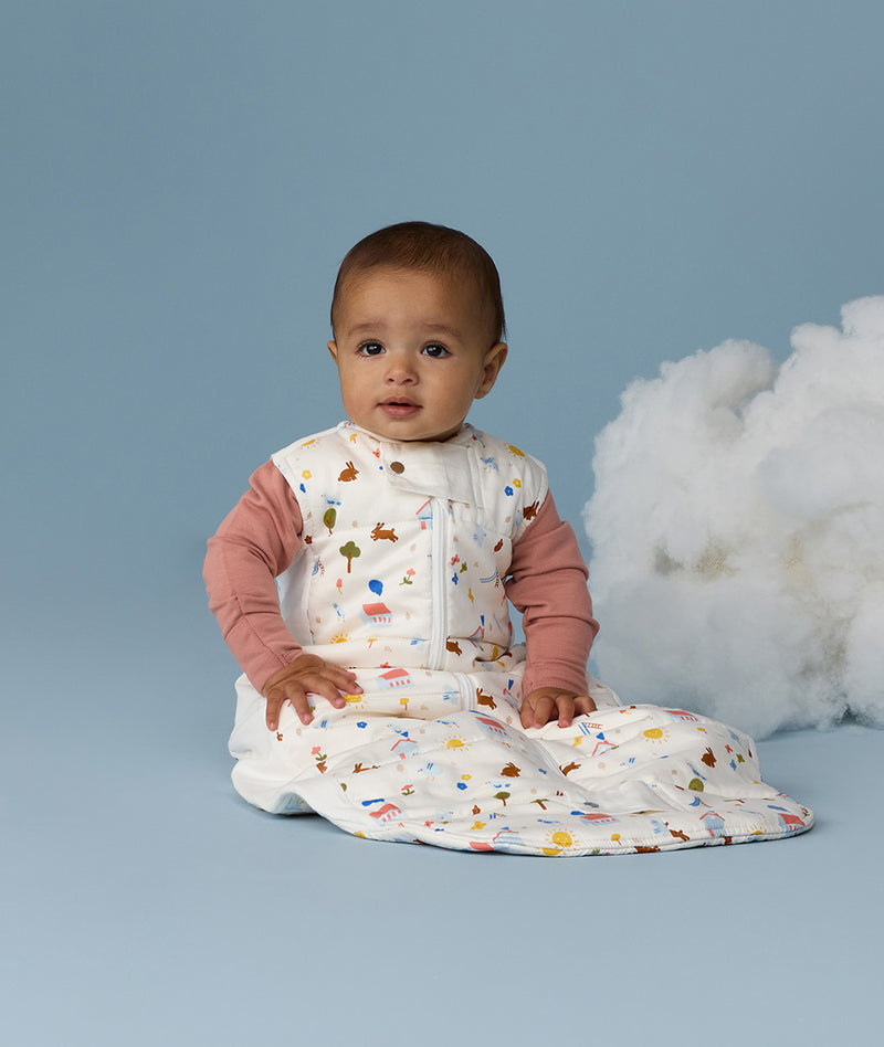 Infant sitting upright wearing a Premium Sleeping Bag 2.5 TOG with a long sleeve layer underneath.