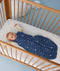 Baby lying in a cot wearing a Premium Sleeping Bag 2.5 TOG with a long sleeve layer underneath.