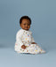 Infant sitting upright, wearing a Premium Sleeping Bag 3.5 TOG Daydream featuring colourful patterns and long sleeves.