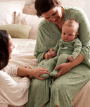 Mum cuddles with baby, wearing matching ergoPouch maternity robe and Layer in the print Willow