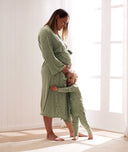 A toddler stands next to a pregnant mum, wrapping their arms around her, wearing matching ergoPouch Layer and Maternity Robe