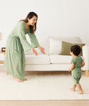 A mum wearing the Matchy Matchy Robe stands with arms outstretched as toddler in matching pyjamas runs toward her