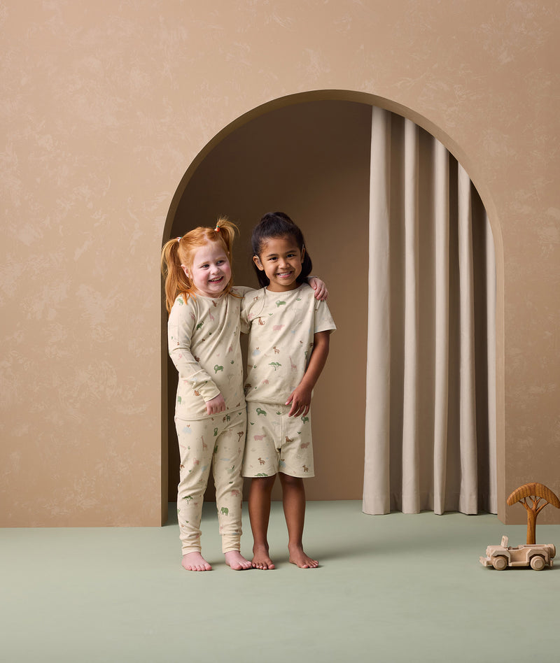 Two preschoolers are wearing ergoPouch two-piece pyjamas Savannah. The child on the left is in long sleeve pyjamas, while the child on the right is in short sleeve ones.