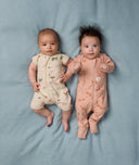Two babies lying side by side wearing ergoPouch Short Sleeve Layer in Savannah and Long Sleeve Layer in Elephant Parade.