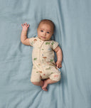 Baby lying on a soft blue sheet, wearing an ergoPouch Short Sleeve Layer, featuring a front zipper and a snug fit.