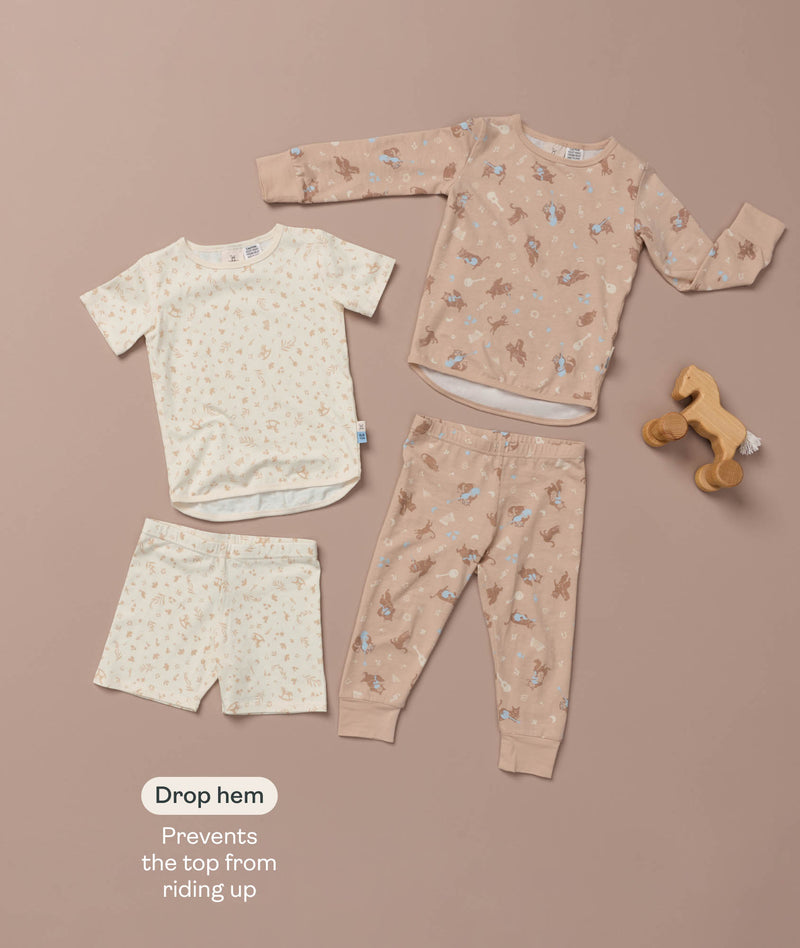 Flat lay of a cream Short Sleeve Pyjama set and a beige Long Sleeve Pyjama set with a wooden toy horse and feature text callout.