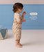 Side profile of a toddler wearing a beige patterned Short Sleeve Pyjama set with a drop hem feature callout.