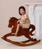 Preschooler wearing beige patterned Short Sleeved Pyjamas, riding a wooden rocking horse.