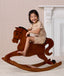 Preschooler wearing beige patterned Short Sleeved Pyjamas, riding a wooden rocking horse.