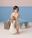 Toddler holding a stuffed bunny with a finger over their lips, wearing a beige patterned Short-Sleeve Pyjama set.