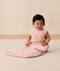 Infant sitting up in a sleeveless pink floral-patterned Sleeping Bag featuring a side zipper.