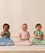 Three infants sitting side by side, wearing ergoPouch Side Zip Sleeping Bags in Dragonflies, Daisies, and Willow.
