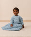 Infant sitting on the floor, wearing a Side Zip Sleeping Bag Dragonflies