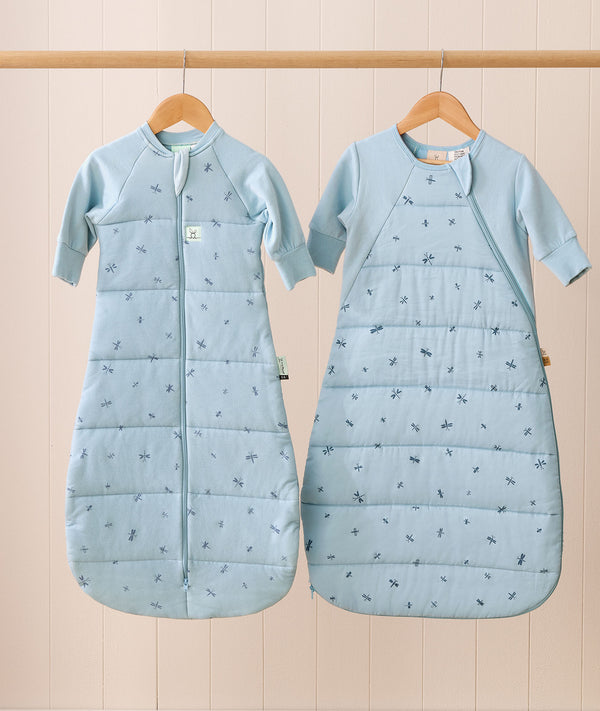 The Jersey Sleeping Bag and Side Zip Sleeping Bag hang side by side on wooden hangers. Both are light blue with small dragonflies pattern; the Jersey Sleeping Bag has a center front zipper, while the Side Zip Sleeping Bag features a diagonal side zipper.