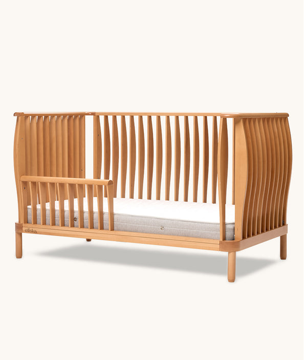 Wooden cot with a slatted design on a white background