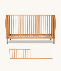 Wooden cot with a separate sideguard on a white background