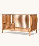Wooden cot with slatted design on a white background