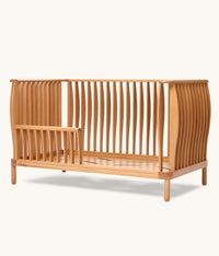 Wooden cot with slatted design on a white background