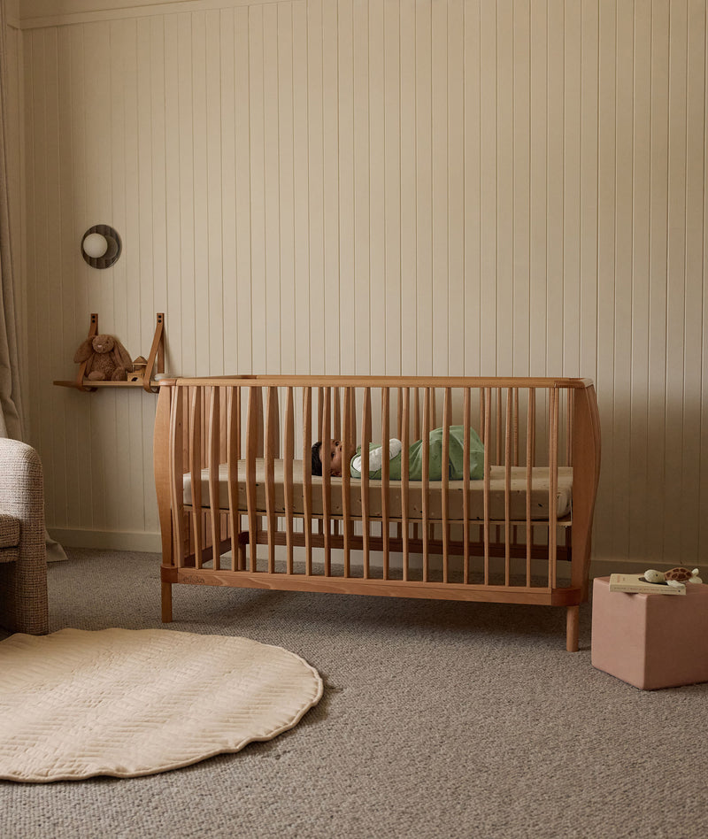 Wooden cot in a nursery with neutral decor